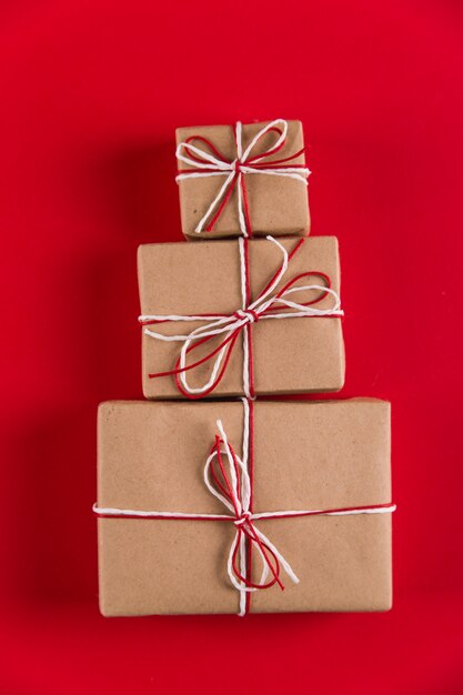 Prezenty z papieru rzemieślniczego i lin w kształcie choinki na czerwonym, świątecznym, z życzeniami copyspace.