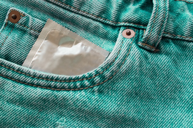 Zdjęcie prezerwatywa w kieszeni zielonych dżinsów. koncepcja bezpiecznego seksu.
