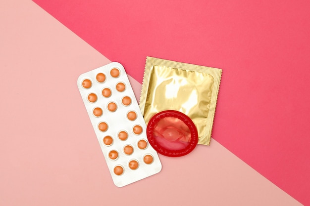 Prezerwatywy i tabletki na dwukolorowej powierzchni