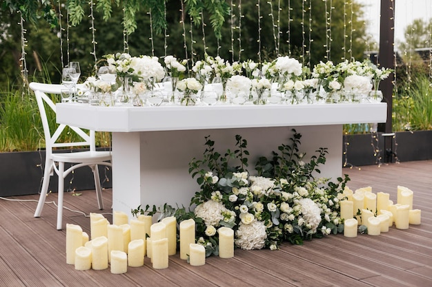 Prezydium dla nowożeńców udekorowane świecami i wazonami z białymi naturalnymi kwiatami
