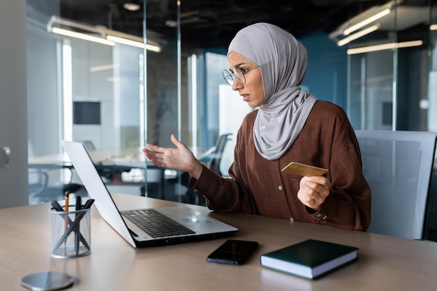 Problem z kartą kredytową młoda arabka siedzi w biurze pracuje z laptopem i posiada kredyt