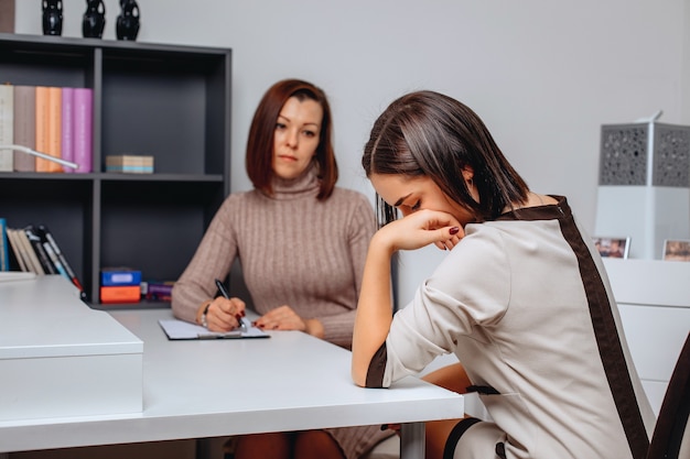 Problemy psychiczne Przygnębiona kobieta trzymająca się za twarz i przychodząca do psychologa. Depresja i apatia.