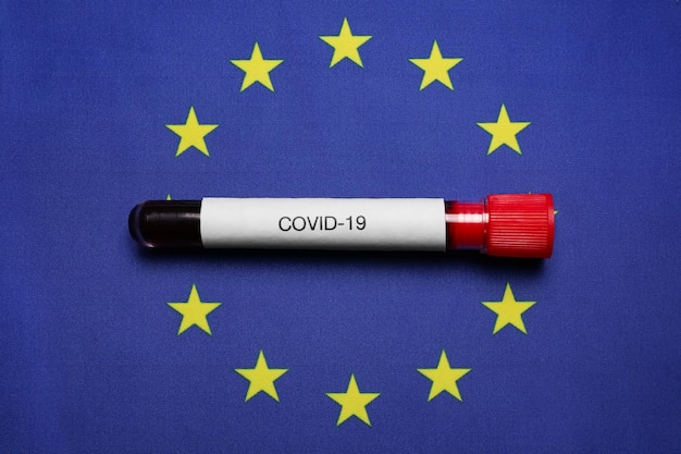 Probówka z próbką krwi na tle flagi Unii Europejskiej, widok z góry Wybuch koronawirusa