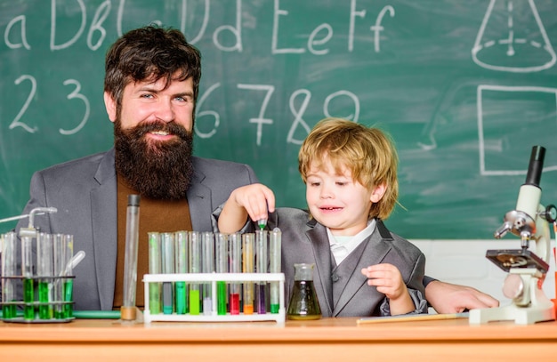 Probówki laboratoryjne i kolby z kolorowymi płynami ojciec i syn w szkole naukowiec przeprowadzający badania naukowe w laboratorium Powrót do nauczyciela szkolnego mężczyzna z chłopcem Innowacja zaczyna się od nas