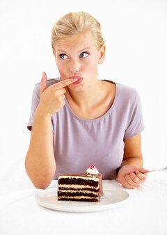 Próbuję małego smaku młoda kobieta smakuje lukier pysznego kawałka ciasta czekoladowego