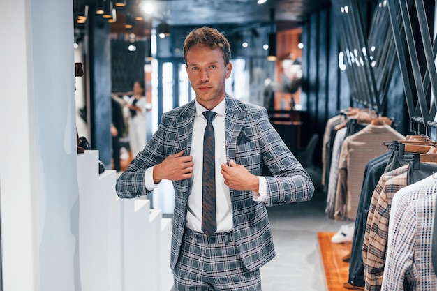 Próbuje nosić Młody facet w nowoczesnym sklepie z nowymi ubraniami Elegancka droga odzież dla mężczyzn