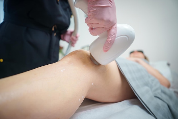 Procedura depilacji laserowej na nodze klienta w salonie kosmetycznym