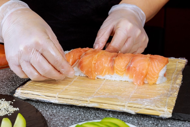 Proces gotowania japońskiej rolki sushi z łososiem.