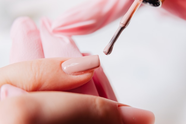 Proces manicure. Manikiurzystka maluje paznokcie. Lakier do paznokci.