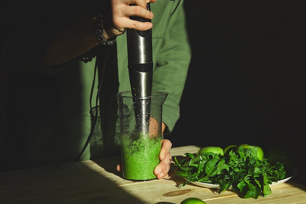 Proces Przygotowania Zielonego Detox Smoothie Z Blenderem, Młody Człowiek Gotuje W Domu Zdrowy Smoothie Ze świeżymi Owocami I Zielonym Szpinakiem, Koncepcja Detoksykacyjna Lifestyle, Napoje Wegańskie.