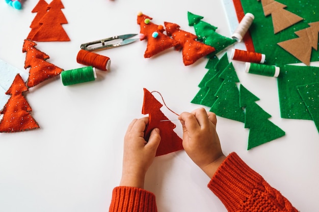 Zdjęcie proces ręcznego szycia miękkich zabawek z filcu i igły do dekoracji choinki bożonarodzeniowej