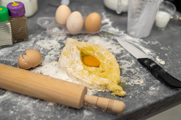 Proces wyrabiania ciasta na pyszne chaczapuri z jajkiem na dużym stole kuchennym Koncepcja gotowania