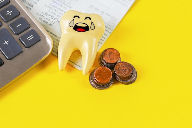 Próchny ząb z płaczącą twarzą kalkulatora i monetami, wydatki na zdrowie zębów