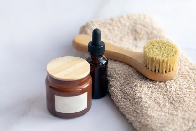Produkty kosmetyczne w ręczniku łazienkowym szczoteczka do twarzy z kroplą serum i mydło złuszczające