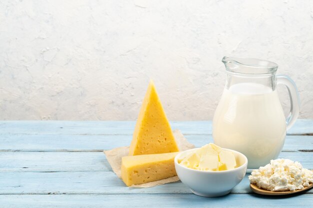 Produkty mleczne ser masło twarożek mleko na stole z białym tłem miejsca na tekst