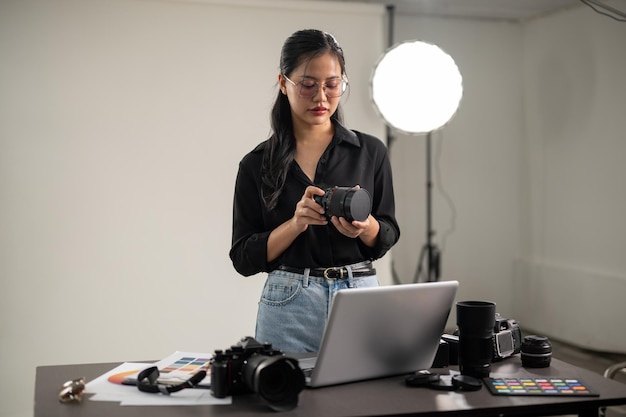 Profesjonalna azjatycka fotograf przygotowuje swój aparat do sesji fotograficznej pracując w studiu