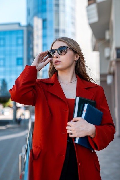 Profesjonalna bizneswoman w garniturze stojąca w pobliżu budynku biurowego ze skrzyżowanymi ramionami