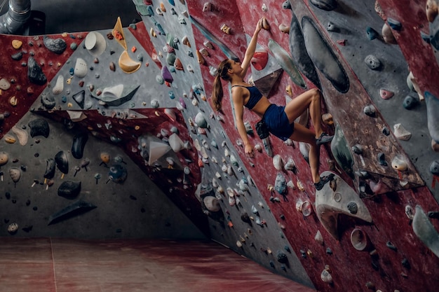 Profesjonalna Kobieta Wspinacz Na ścianie Bouldering W Pomieszczeniu.