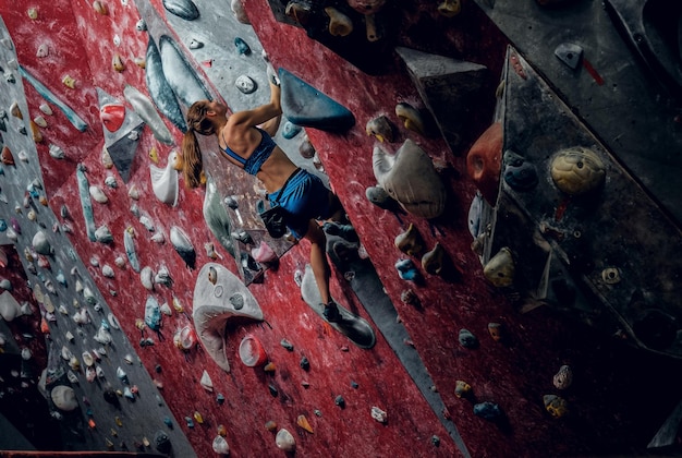 Profesjonalna Kobieta Wspinacz Na ścianie Bouldering W Pomieszczeniu.