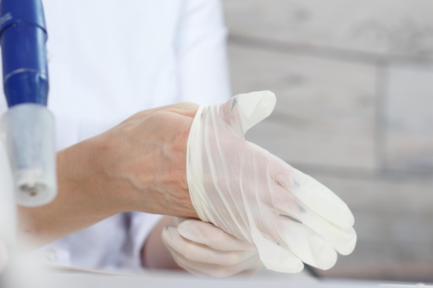 Profesjonalna manikiurzystka zakłada białe rękawiczki medyczne