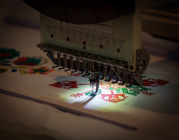Profesjonalna maszyna do szycia haft tekstylny, zbliżenie. Tkanina odzieżowa, nikt. Szycie, technologia robótek ręcznych