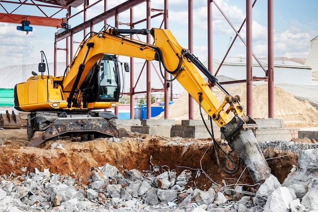 Profesjonalna rozbiórka konstrukcji żelbetowych przy użyciu przemysłowego młota hydraulicznego z koparką. Pręty okuć metalowych. Wrak i okruchy betonu.