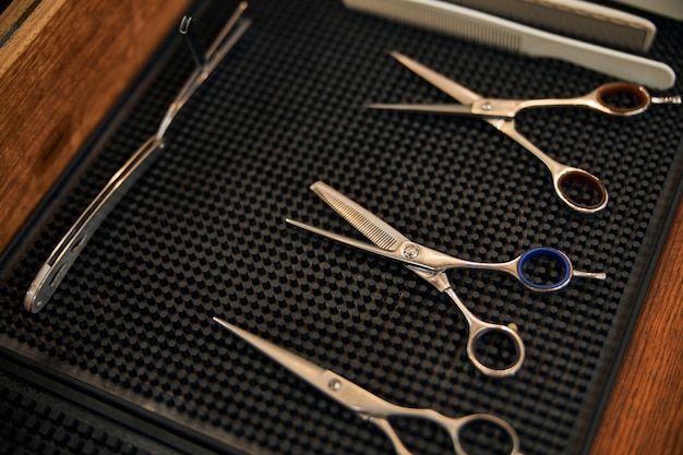Zdjęcie profesjonalne nożyczki fryzjerskie i brzytwa na czarnej gumowej macie