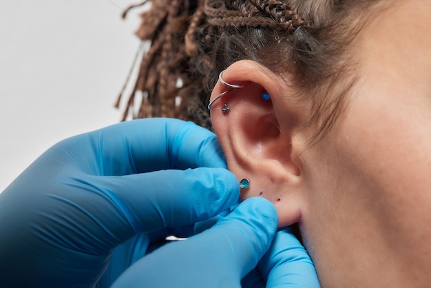 Profesjonalne trzymanie klejnotu piercingu dnia tuż przed wkręceniem kulki typu Tragus