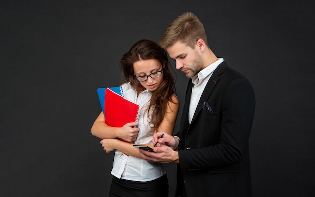 Profesjonalni brokerzy używający smartfona do zadań biznesowych na ciemnym tle mobilnym