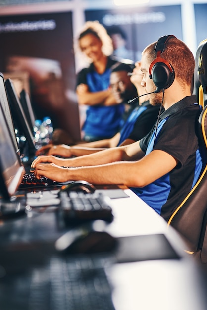Profesjonalni Gracze Cybersport Noszący Słuchawki Siedzący W Rzędzie Uczestniczący W E-sporcie