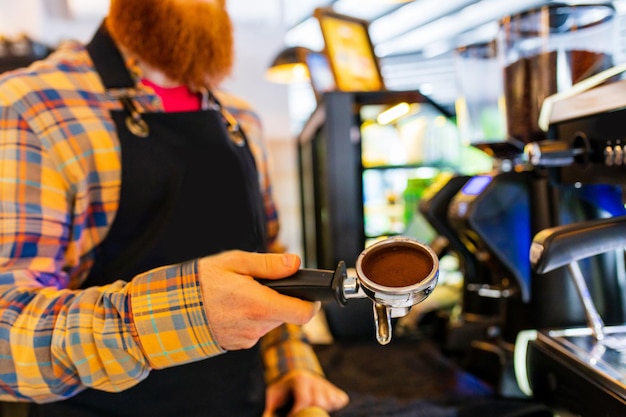 Profesjonalny barista młody rudowłosy imbir brodaty mężczyzna w czarnym fartuchu pracujący w kawiarni