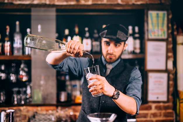 Profesjonalny barman wlewający rum do koktajli w pubie barowym lub restauracji
