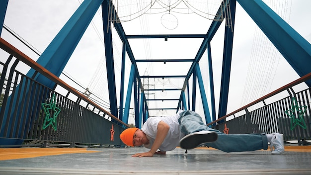 Profesjonalny break dancer wykonuje street dance footstep na moście z entuzjazmem