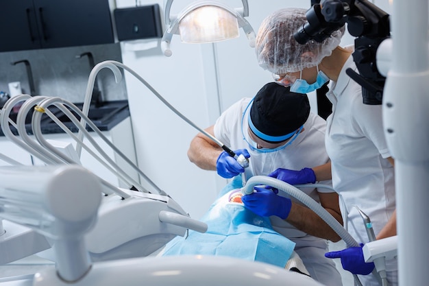 Profesjonalny dentysta bada zęby pacjenta za pomocą sprzętu dentystycznego i trzyma instrumenty dentystyczne w pobliżu ust Dentysta Gabinet stomatologiczny