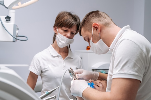 Profesjonalny dentysta i pielęgniarka robi operację na pacjentce. Zespół dentystów z klientem w gabinecie stomatologicznym, higiena jamy ustnej, zdrowe zęby, koncepcja stomatologii