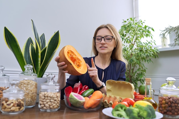 Profesjonalny dietetyk kobieta w średnim wieku siedzi przy stole z dynią żywności