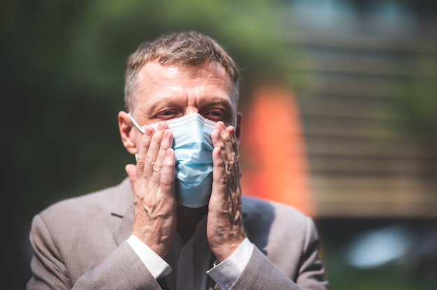 Zdjęcie profesjonalny dorosły biznesmen noszący chirurgiczną maskę na twarz w celu ochrony przed koronawirusem covid-19