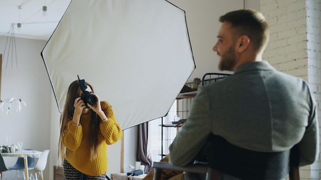 Profesjonalny fotograf kobieta robi zdjęcie modelki biznesmena z aparatem cyfrowym w studio