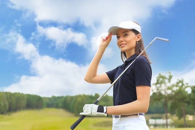 Profesjonalny golfista trzymając klub golfowy na polu i odwracając. Młoda kobieta stojąc na polu golfowym w słoneczny dzień.