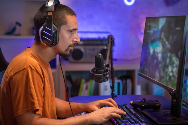 Profesjonalny gracz przesyłający strumieniowo i grający w gry wideo online na komputerze Kolorowe neonowe światła Led