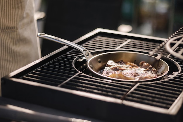 Profesjonalny grill na świeżym powietrzu Zbliżenie męskiego szefa kuchni przygotowującego stek Tbone na patelni