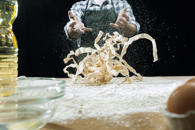 Profesjonalny kucharz posypuje ciasto mąką lub piecze chleb przy kuchennym stole