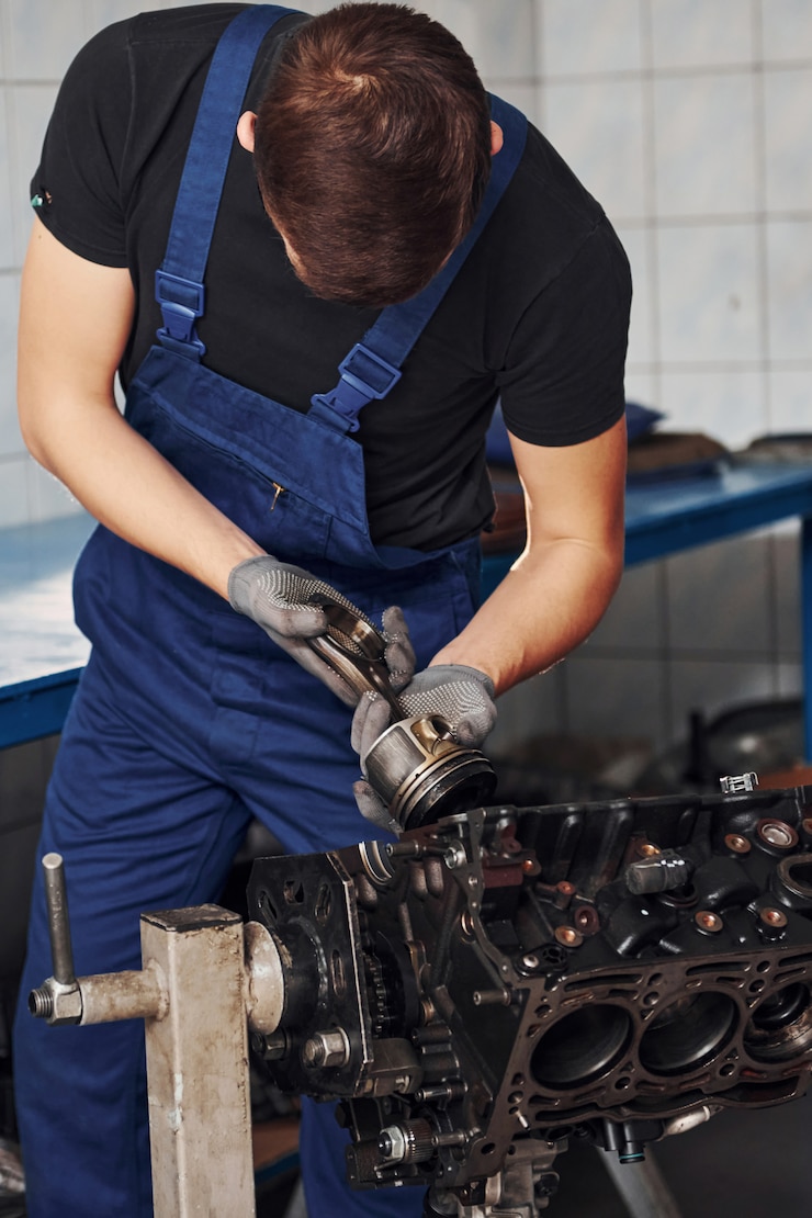 Zdjęcie profesjonalny mechanik w garażu współpracuje z uszkodzonym silnikiem samochodowym