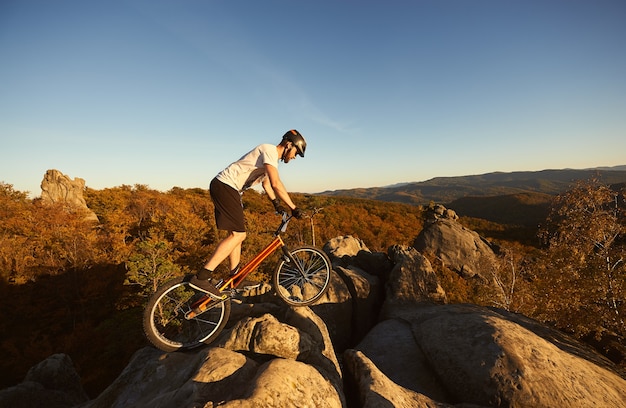 Profesjonalny rowerzysta balansujący na rowerze próbnym o zachodzie słońca