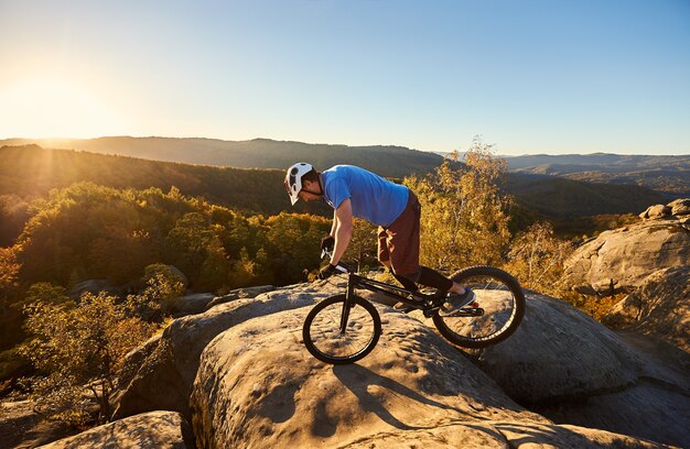 Profesjonalny rowerzysta balansujący na rowerze trialowym o zachodzie słońca