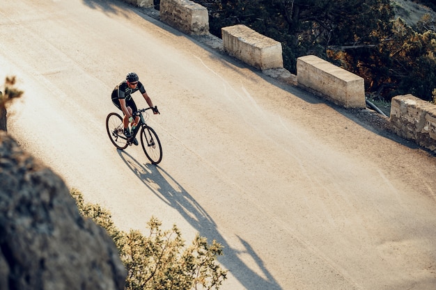 Profesjonalny rowerzysta na górskiej drodze o wschodzie słońca