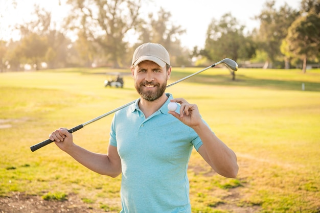 Profesjonalny sport odkryty pokazujący piłkę męski golfista na profesjonalnym polu golfowym portret golfisty w czapce z klubem golfowym wesoły mężczyzna po grze na zielonej trawie letniej aktywności