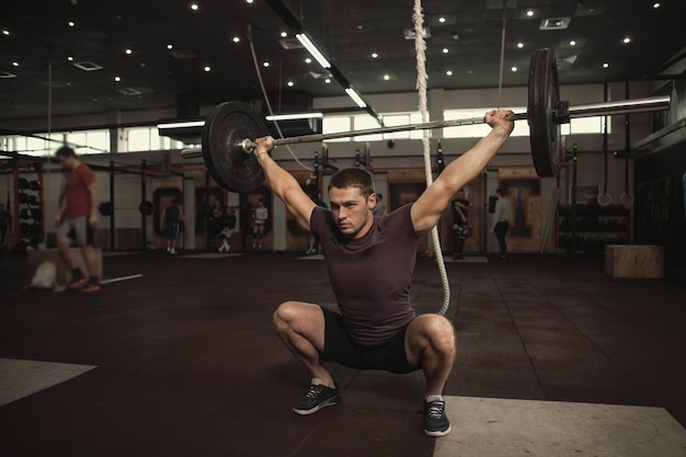 Profesjonalny sportowiec cross fit trenujący ciężką sztangą, wykonujący przysiady