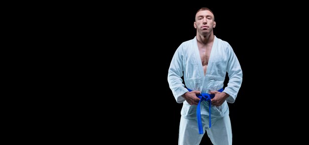 Zdjęcie profesjonalny sportowiec stoi na siłowni w kimono z niebieskim paskiem. koncepcja karate, jiu-jitsu, sambo, judo. różne środki przekazu