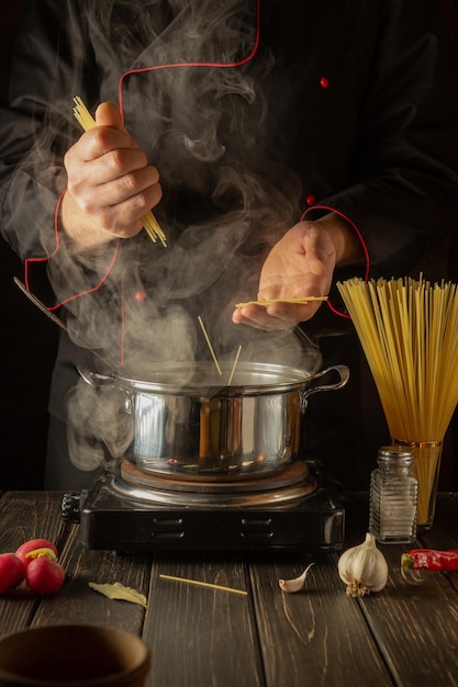 Profesjonalny szef kuchni przygotowuje włoskie makarony Kucharz trzyma w kuchni spaghetti Kuchnia europejska